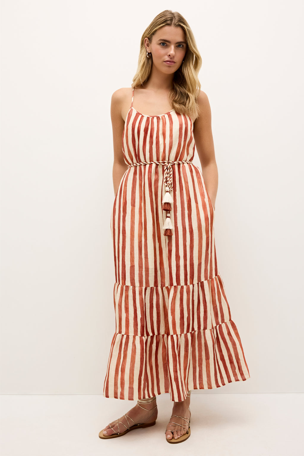 Sleeveless maxi dress with vertical rust and cream stripes and tassel belt