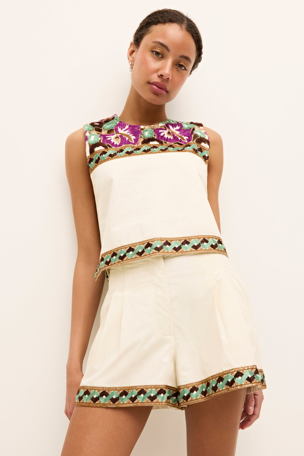 Sleeveless ivory top with vibrant floral embroidery at neckline and hem