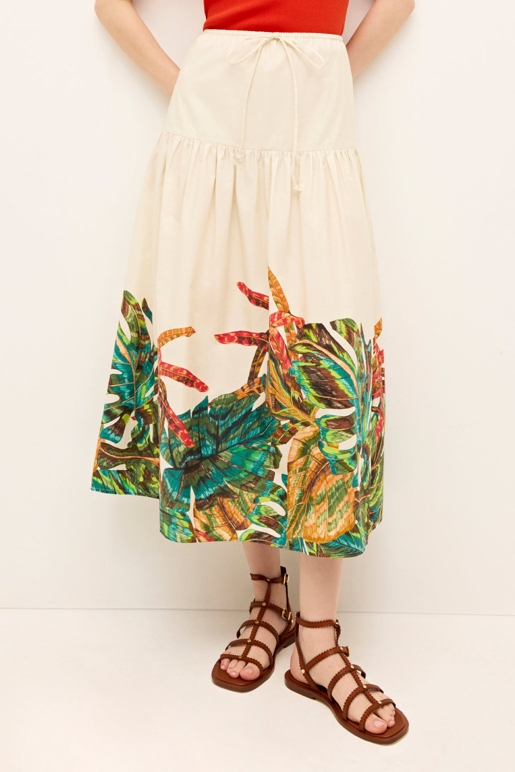 Cream colored A-line midi skirt with a tropical leaf print along the hem and an adjustable drawstring waist