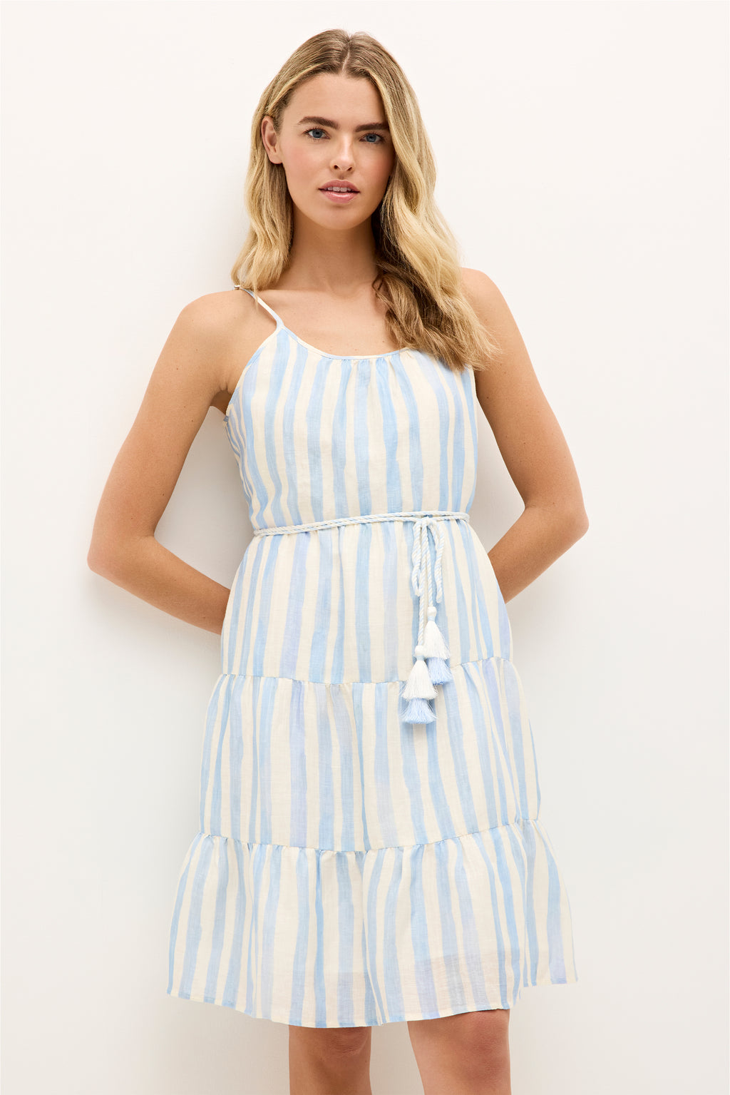 Sleeveless tiered dress with blue and white vertical stripes and braided tassel belt