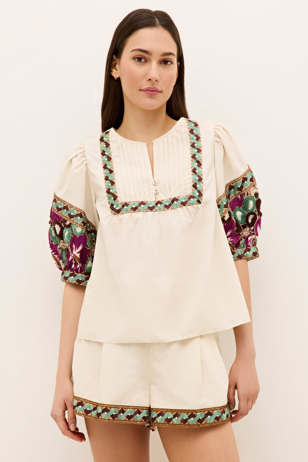 Cream top with split neckline and colorful embroidered sleeves