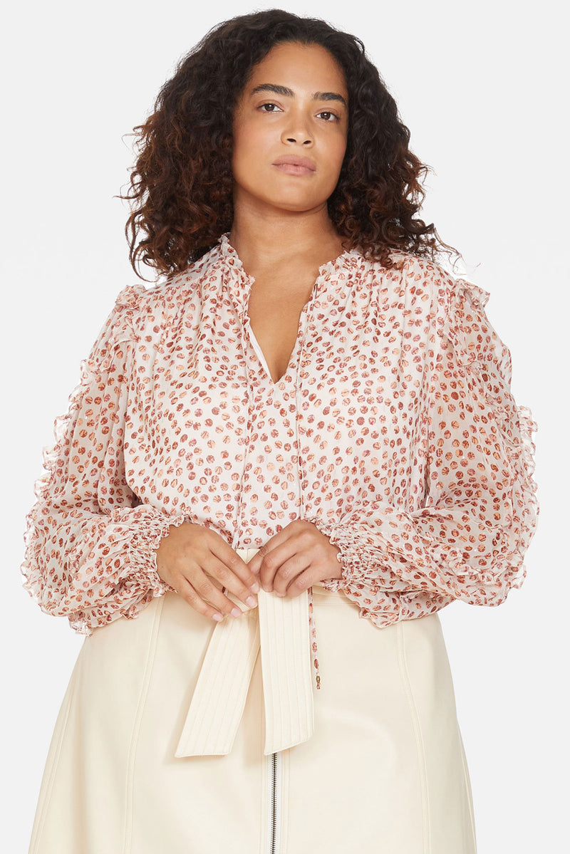 Long sleeve blouse with a lined bodice underneath a monochrome pink dot patterned sheer overlay and ruffle details down the sleeve