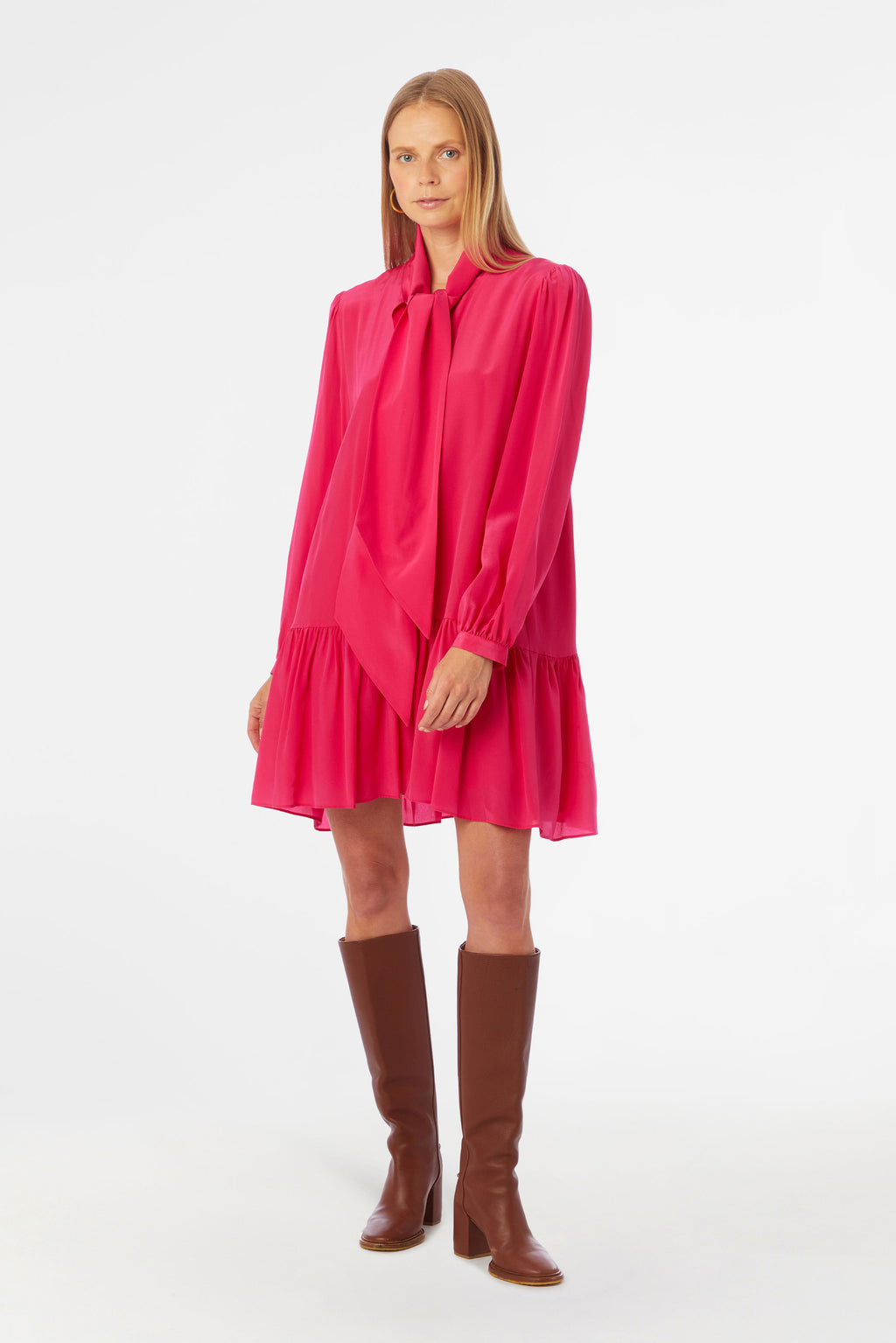Pink mini dress with large bow around the neck, long sleeves, and button cuffs