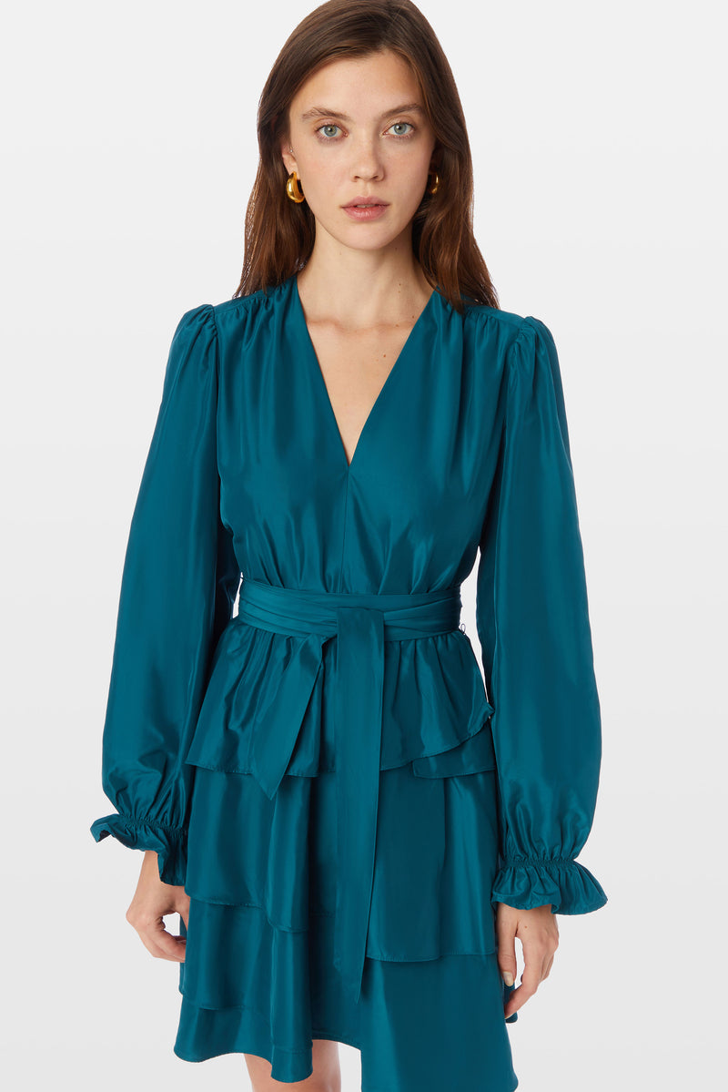 Deep teal blue dress with a v-neckline, long cuffed sleeves, and layered tier skirt