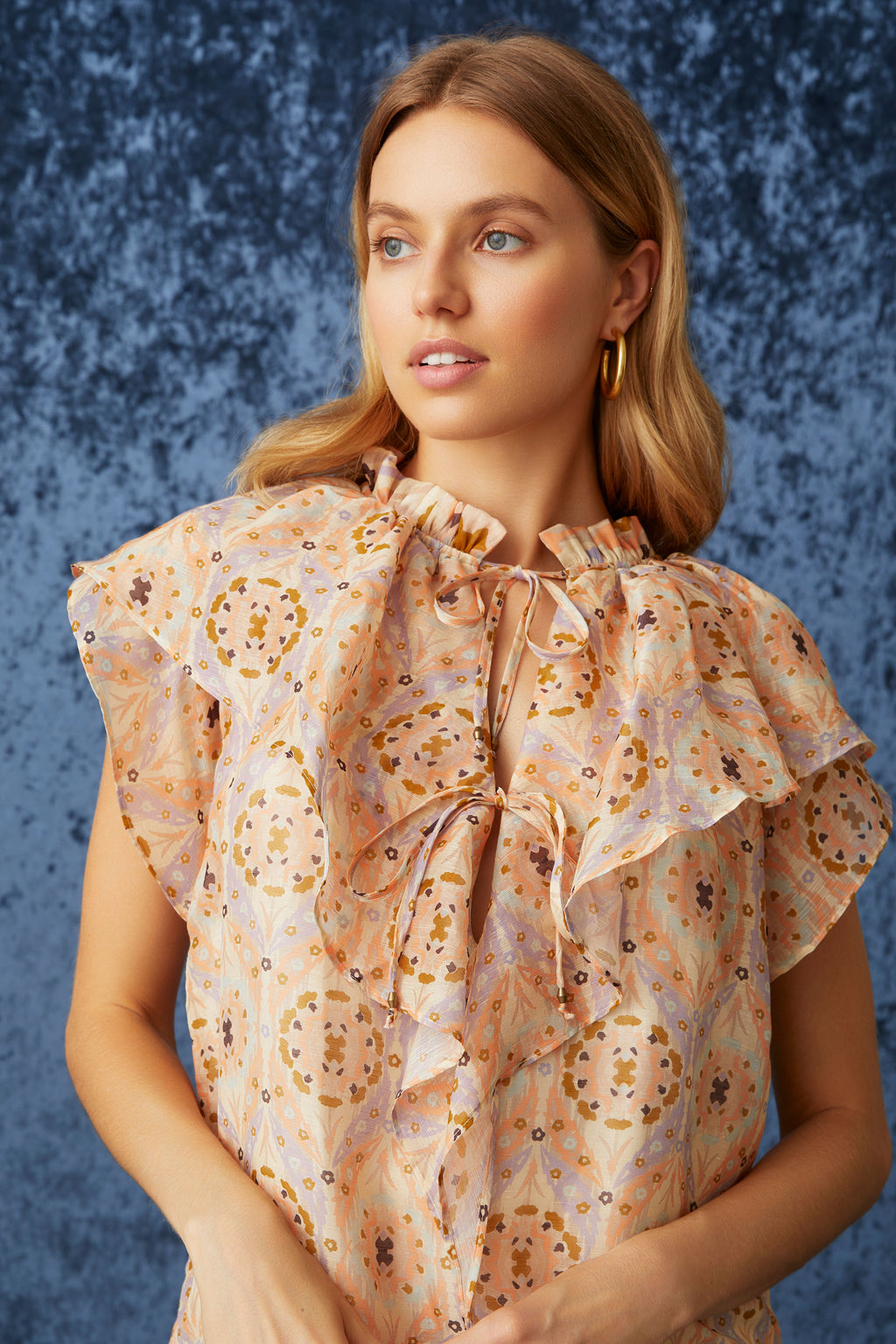 Short sleeve top in a pink geometric print with short ruffled sleeves and large ruffled v-neckline