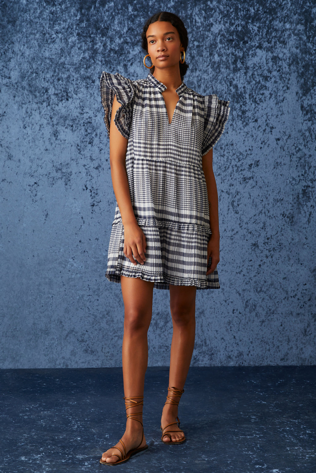 Short tiered dress with ruffle detailing around the neck and large flutter sleeves