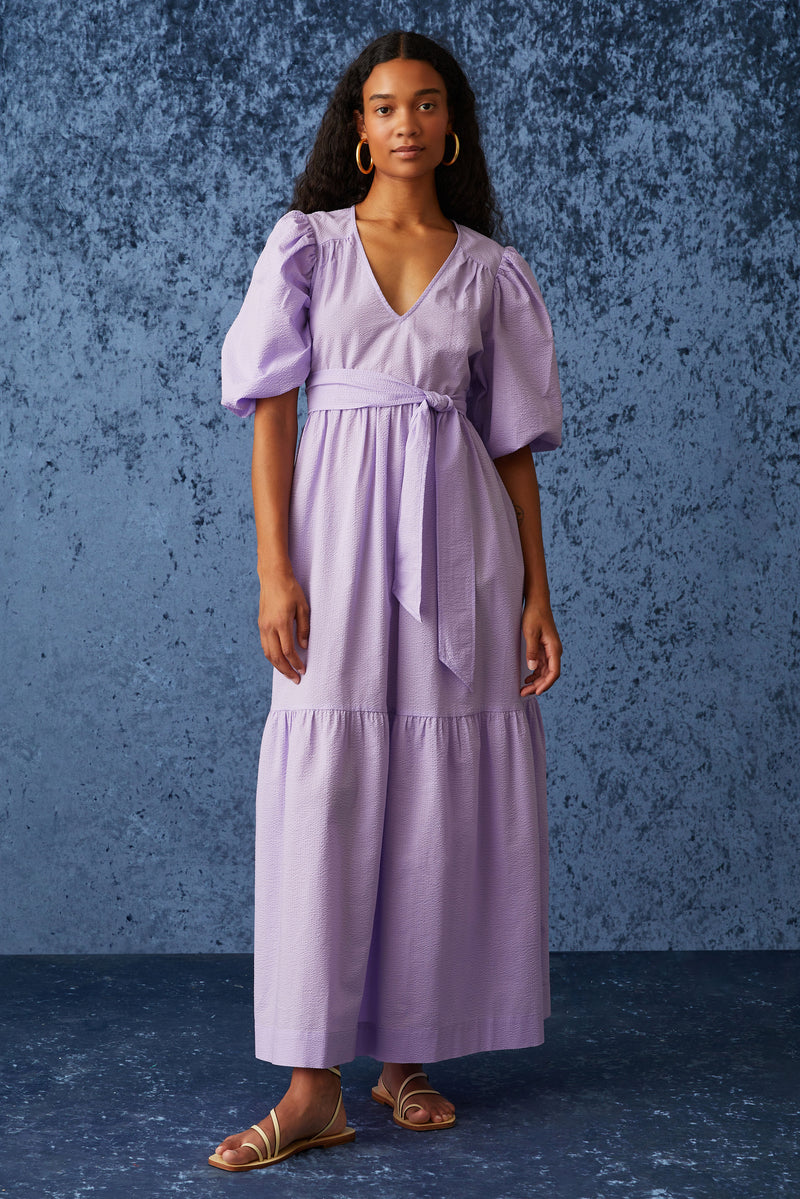 Maxi dress in a light purple color with short puff sleeves and a sash tie belt at the waist