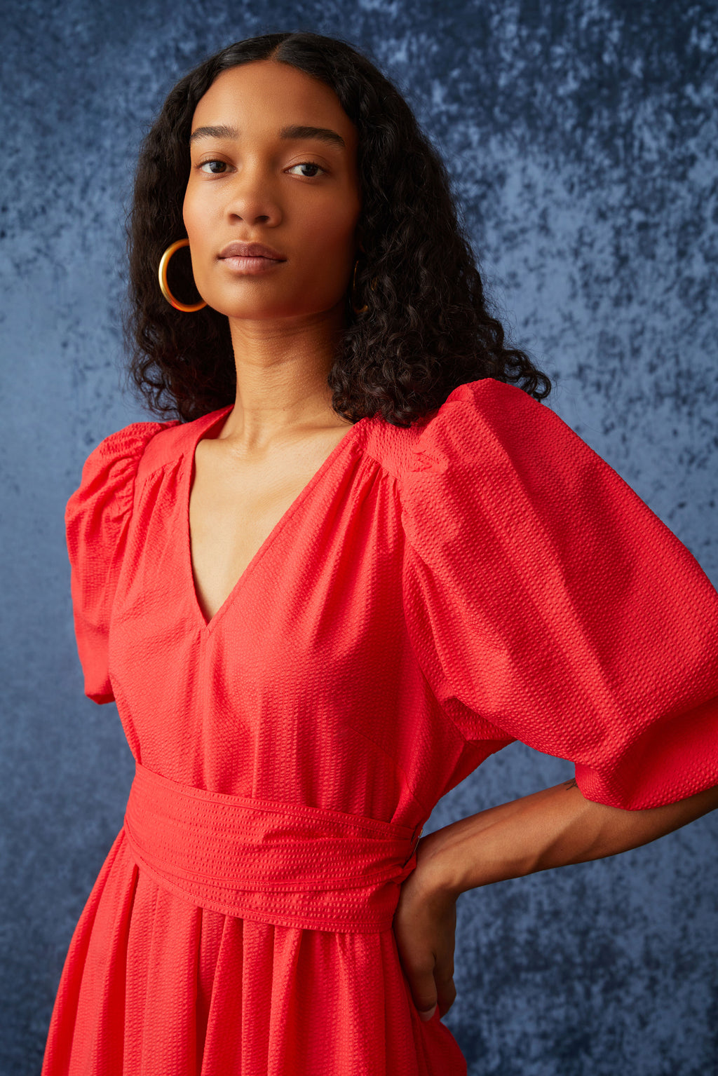 Maxi dress in a bright red color with short puff sleeves and a sash tie belt at the waist