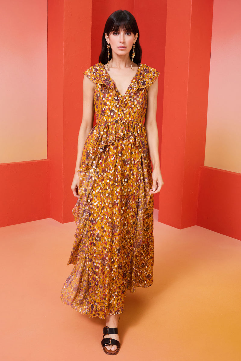 Long flowy dress in a harvest floral with gold detailing and a ruffled v-neckline in the front and back of the dress