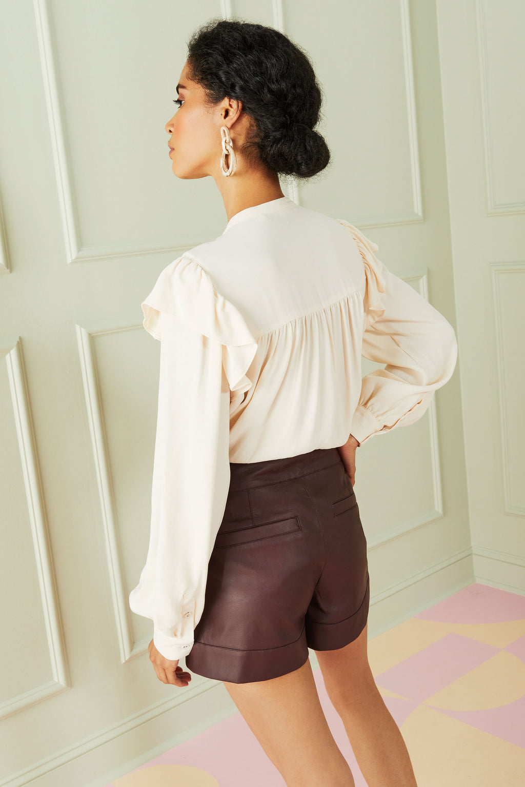 long sleeve ruffle top worn with leather shorts