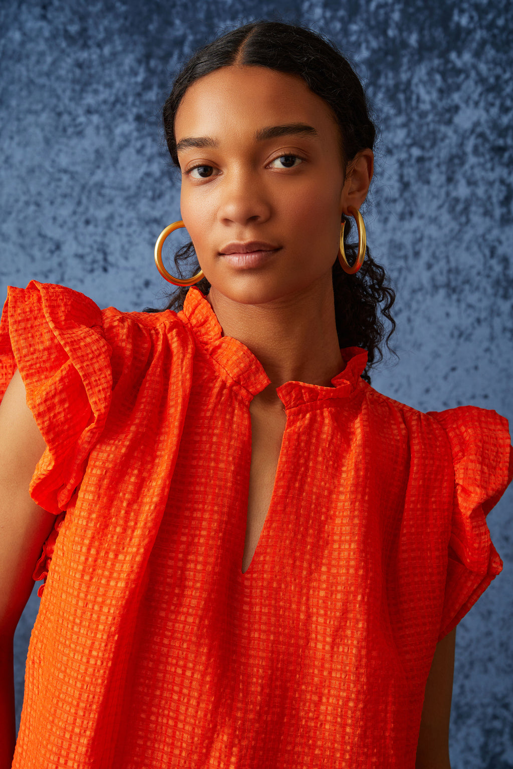 Short ruffle sleeve blouse with v-neck in a solid orange color