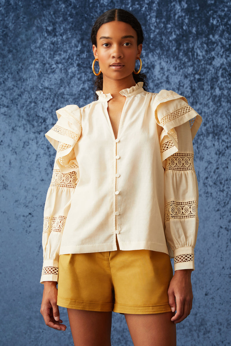 Long sleeve blouse with ruffle detailing at the top of shoulder and embroidered lace cuffs going down the sleeve 