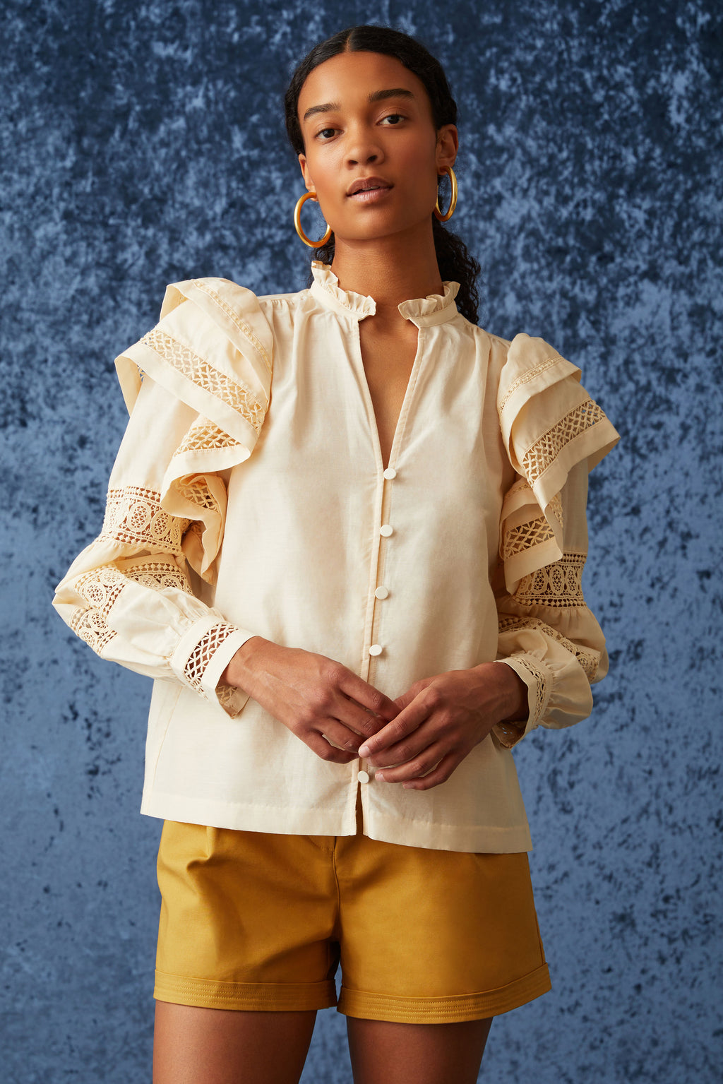 Long sleeve blouse with cuffs at the sleeve and ruffled v-neckline in a solid peach color 