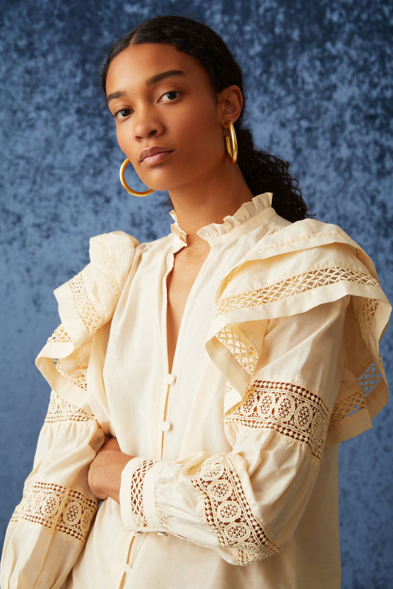 Long sleeve solid peach blouse with v-neckline and functional buttons going down the front